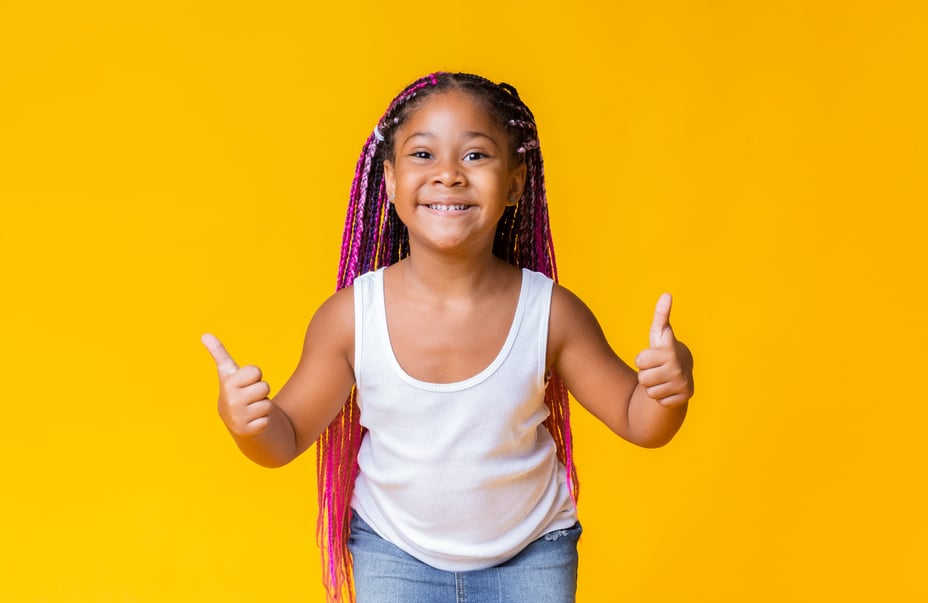 Happy black little girl with afro-braids showing thumbs up